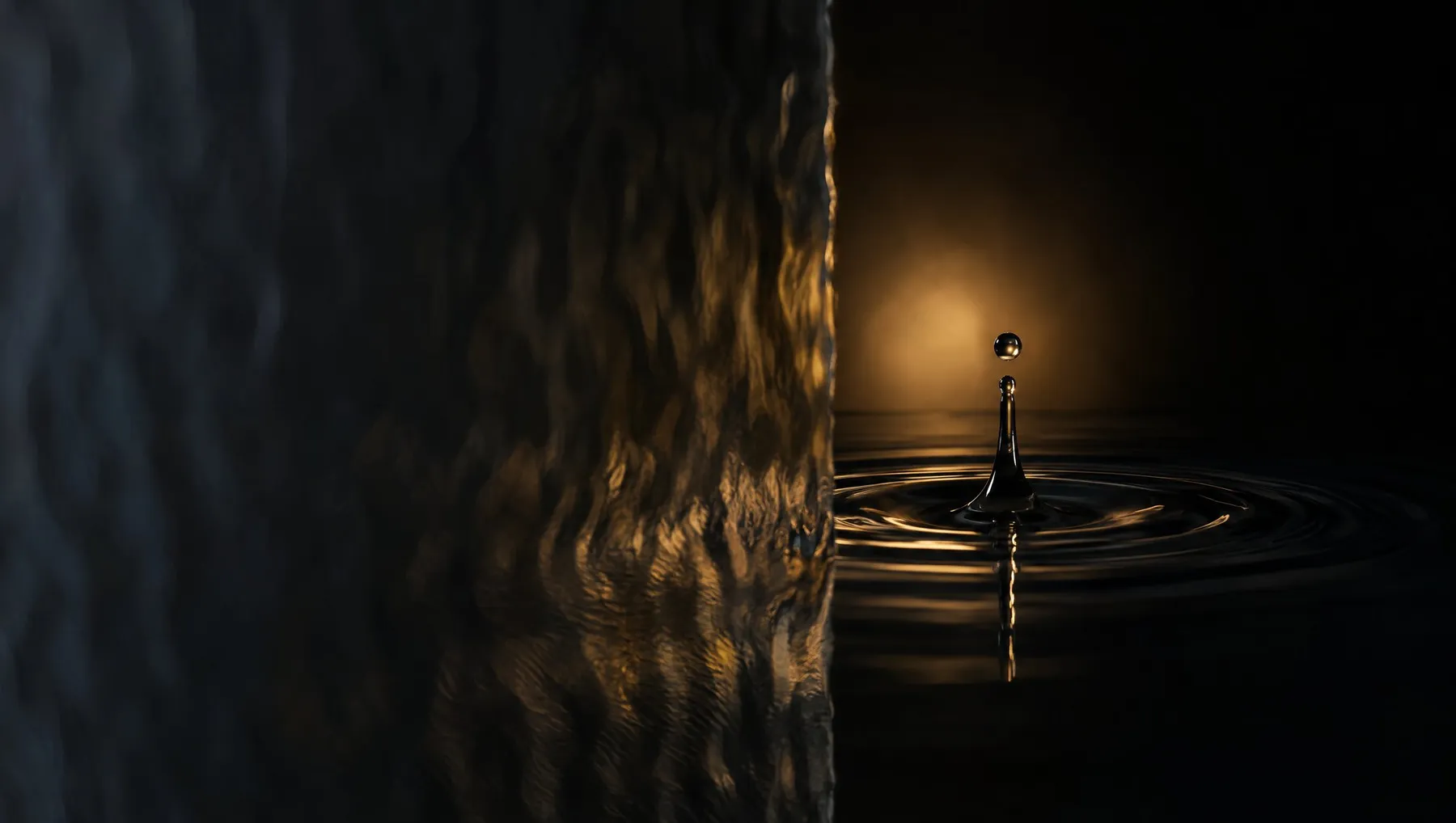 A drop of water landing in still water, half seen through wave glass.