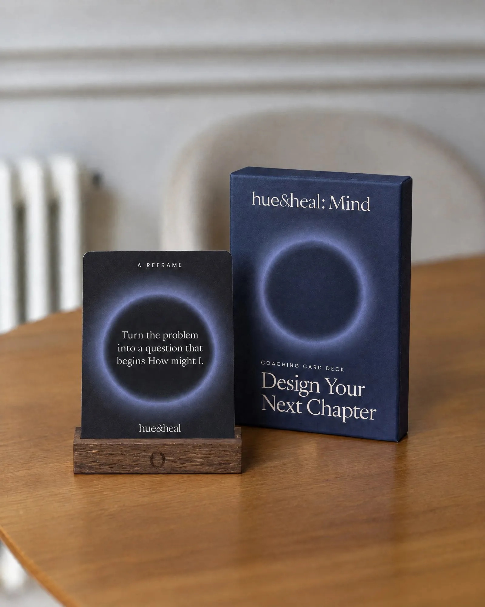 The printed Design Your Next Chapter deck on a dark oak stand beside its box.